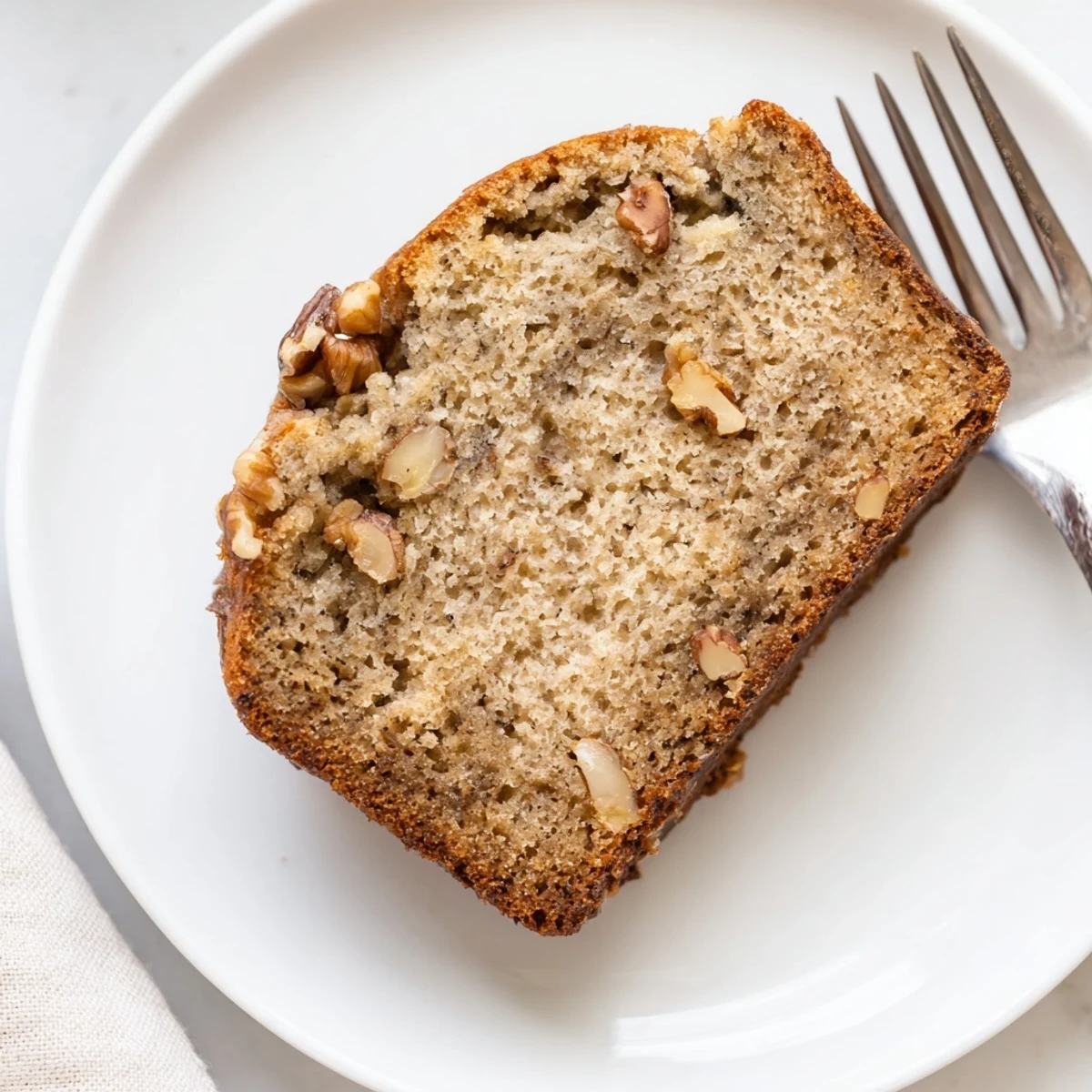 Golden brown moist banana bread loaf sliced on a wooden cutting board with soft texture visible