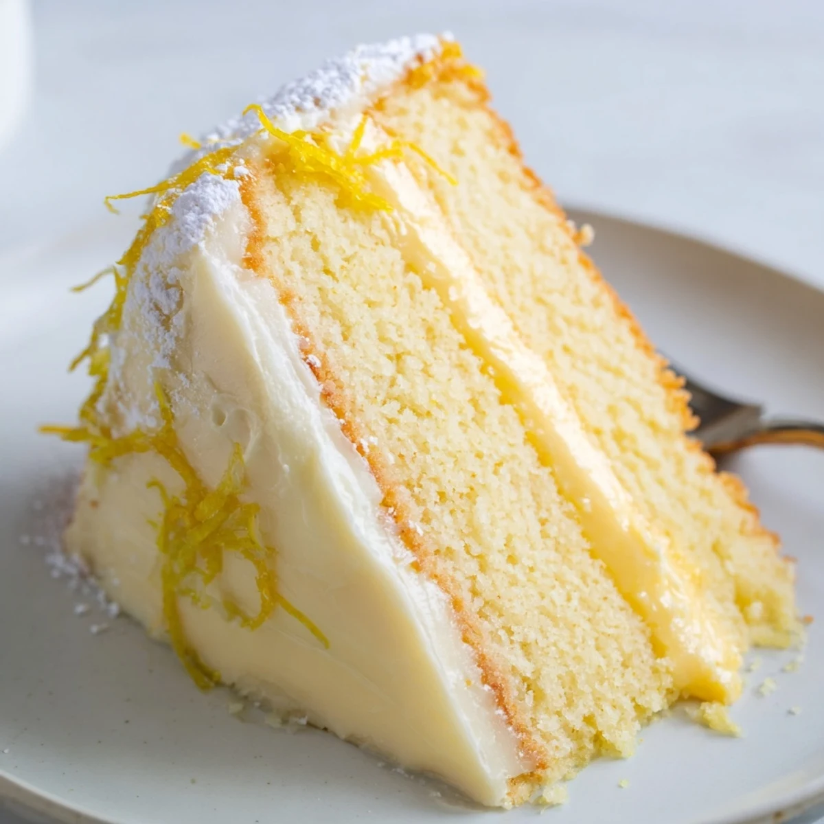 Slice of tangy Italian lemon cream cake showing tender sponge and bright lemon cream center