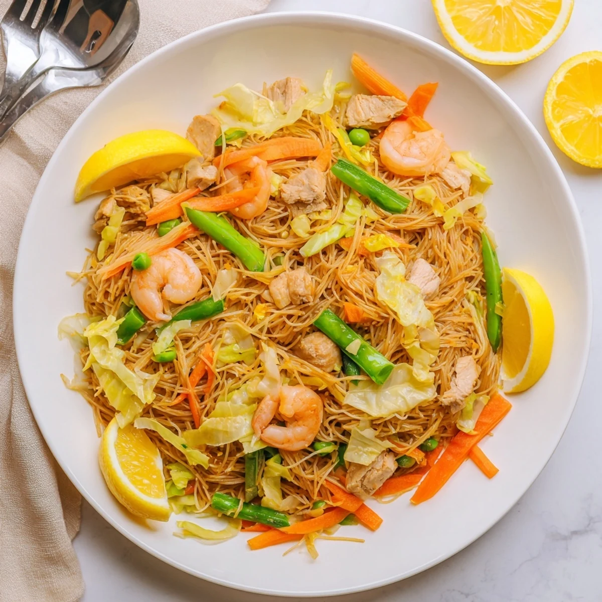 Steaming plate of traditional Pancit Bihon featuring translucent rice noodles tossed with crisp cabbage, carrots, and succulent seafood