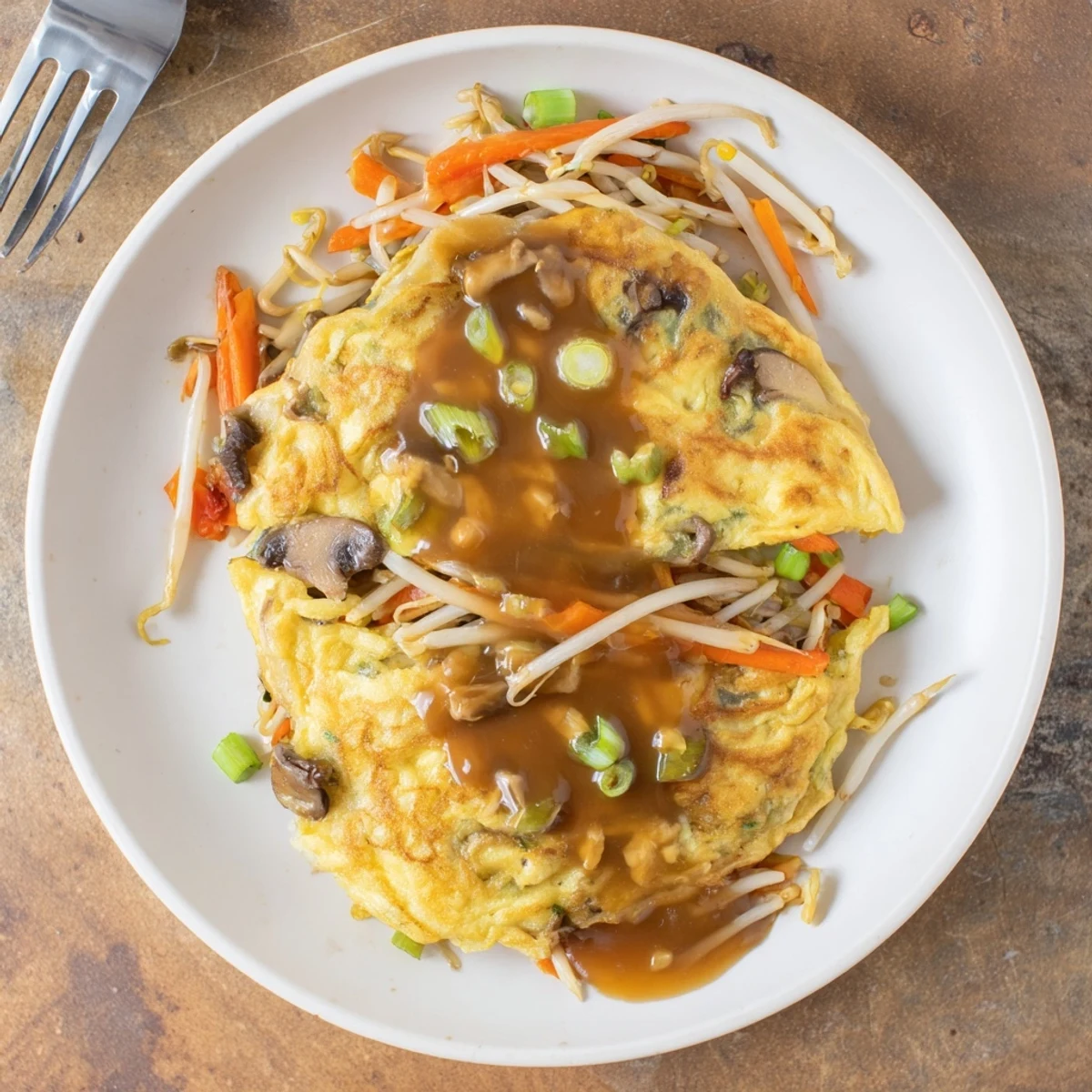 Golden crispy Egg Foo Young patties topped with rich savory brown gravy on white plate