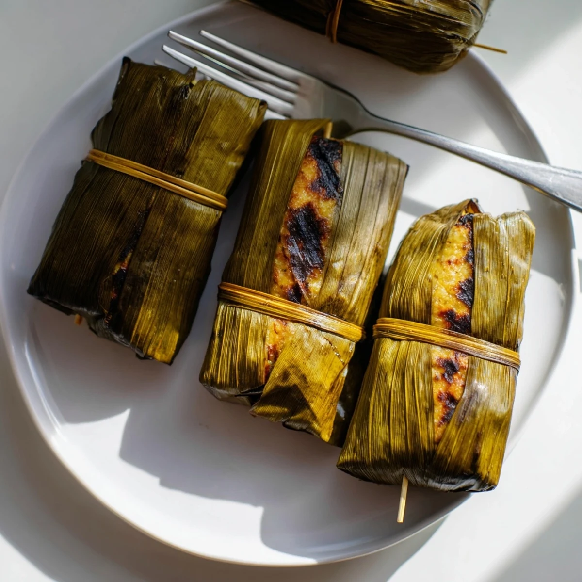 Golden Malaysian Otak Otak aromatic fish parcels served warm on traditional banana leaves