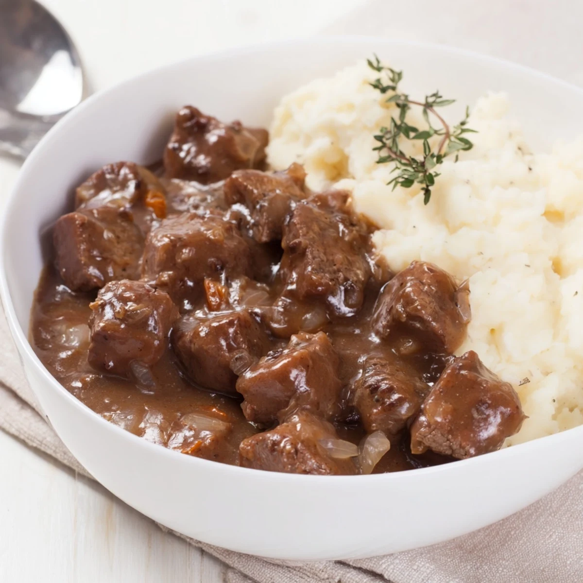 Slow cooker beef tips and gravy served over creamy mashed potatoes with fresh parsley garnish