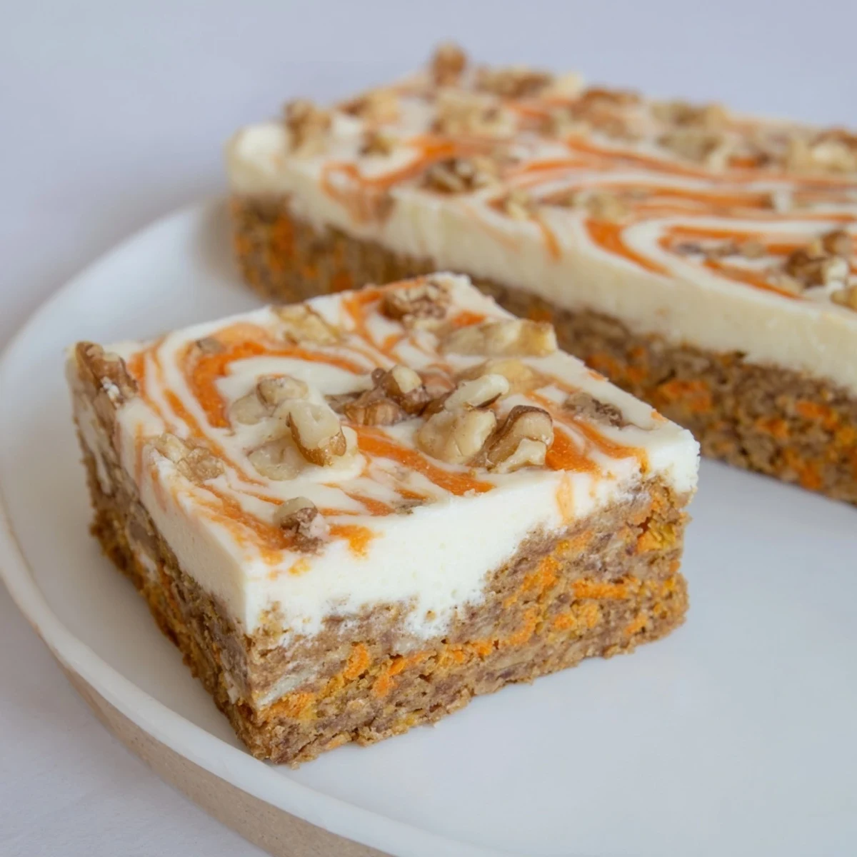Golden carrot cake cream cheese bars with marbled swirls and visible grated carrot bits