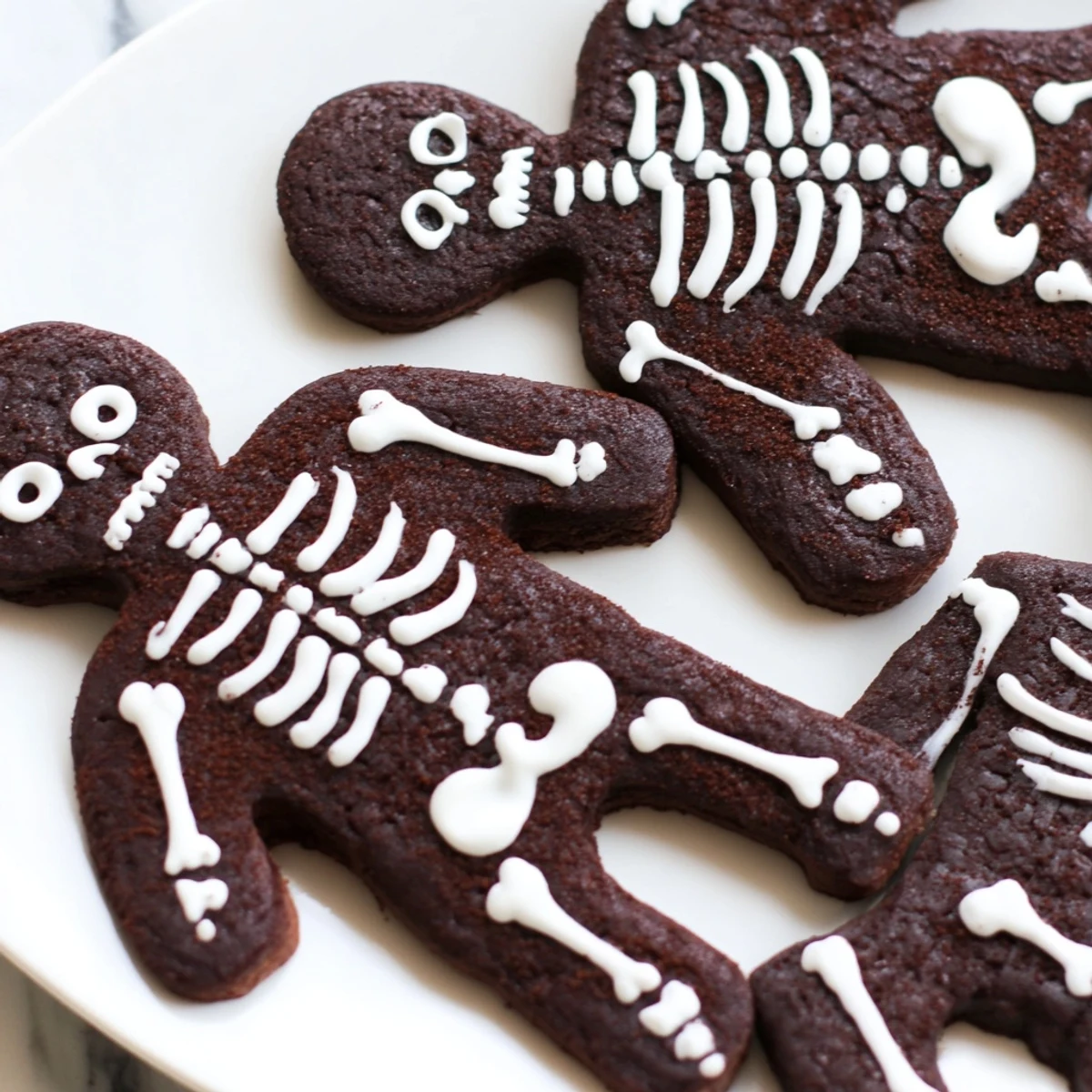 Chocolate Cinnamon Skeleton Cookies decorated with white royal icing on a rustic baking sheet