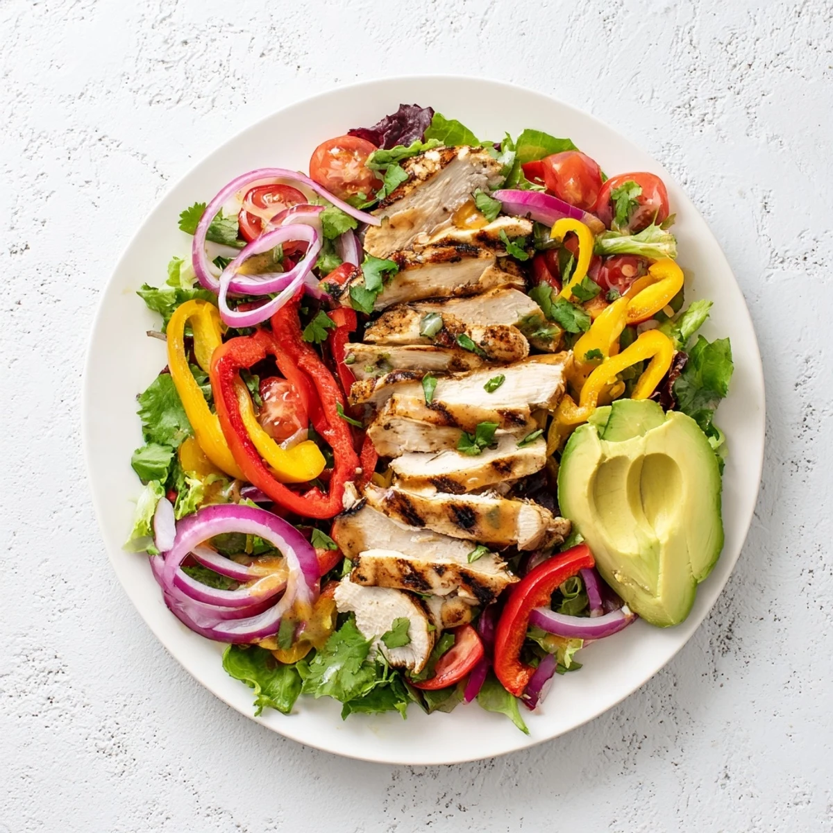 Colorful grilled chicken fajita salad plated with sliced peppers, avocado, and fresh cilantro garnish