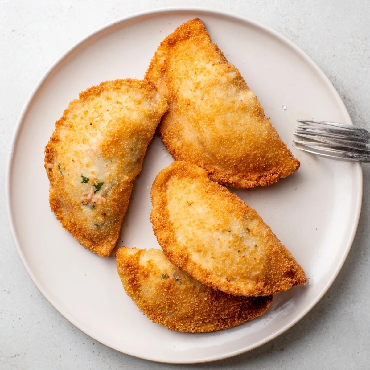 Golden Portuguese shrimp rissois arranged on a white platter with fresh parsley garnish