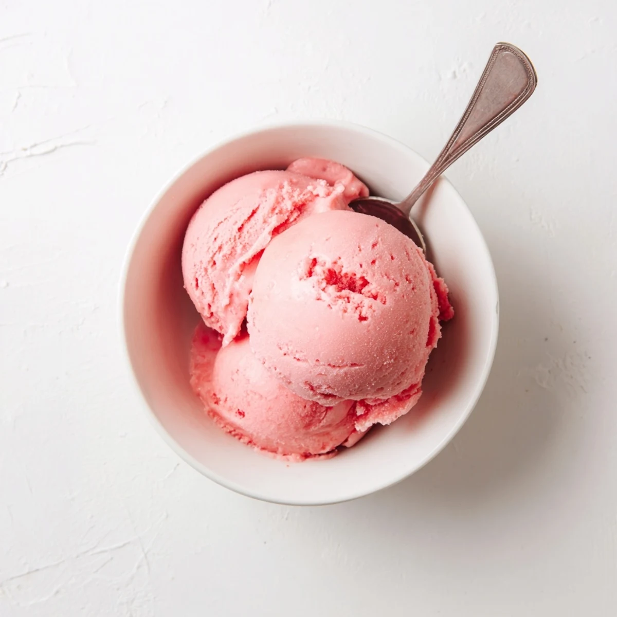 Smooth homemade watermelon ice cream swirled into a frosty glass container topped with chocolate chip "seeds"