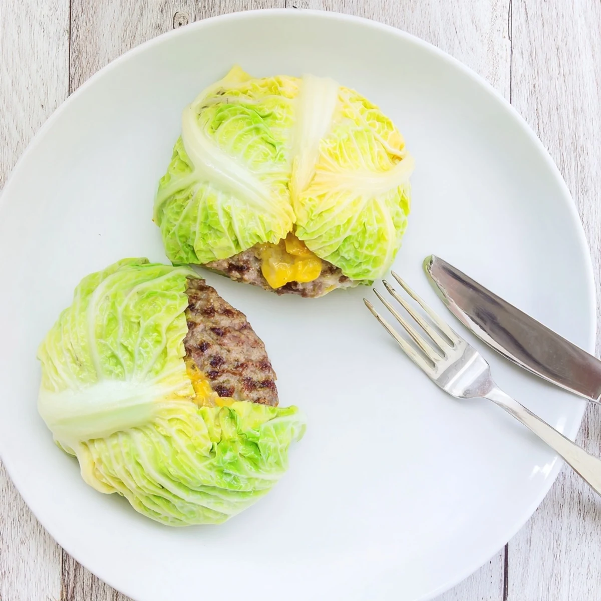 Golden oven baked cabbage burger with melted cheddar inside tender green leaves