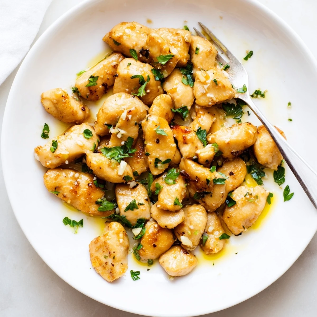 Golden brown garlic butter chicken bites sizzling in a skillet with fresh parsley garnish