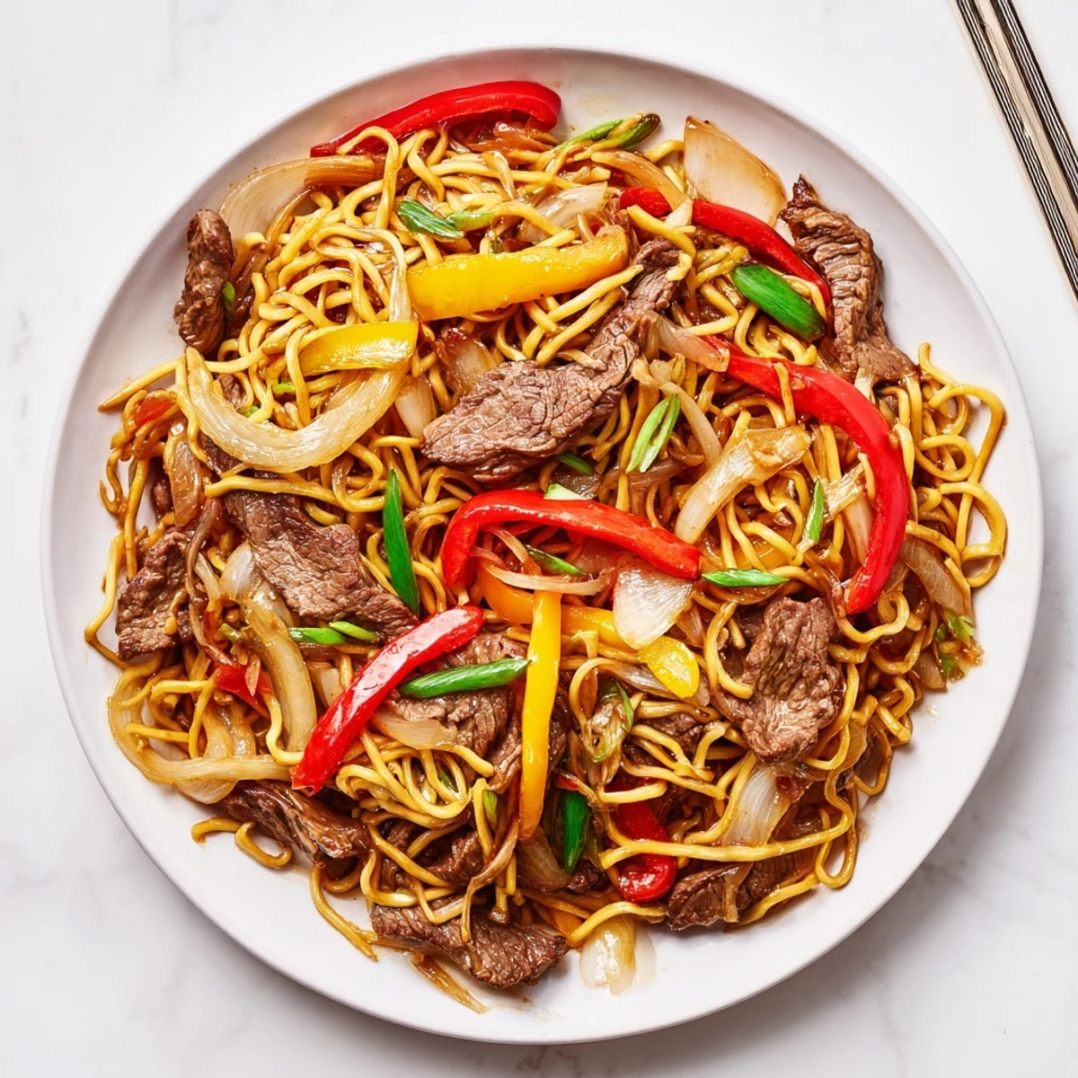 Steaming plate of beef chow mein featuring tender meat and vibrant bell peppers