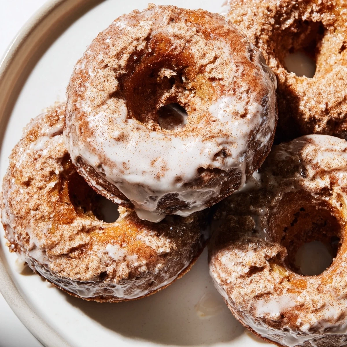 Golden brown banana bread donuts topped with sweet cinnamon glaze on a wire cooling rack