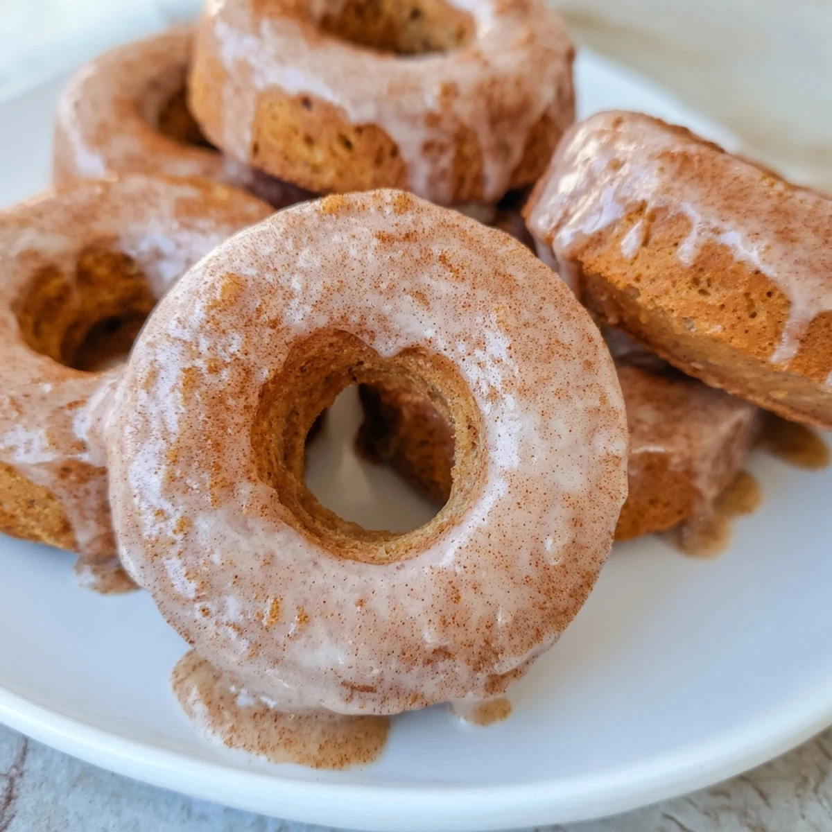 Soft banana bread donuts drizzled with white icing and dusted with warm ground cinnamon