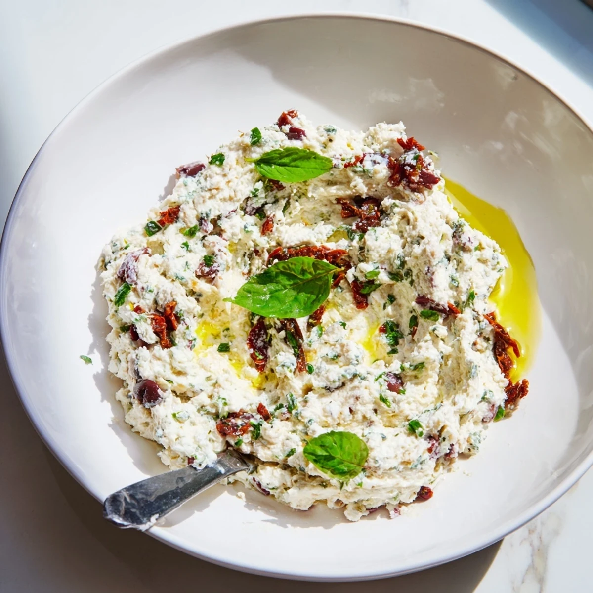 Rustic bowl of Italian Style Olive and Cheese Spread served alongside toasted baguette slices