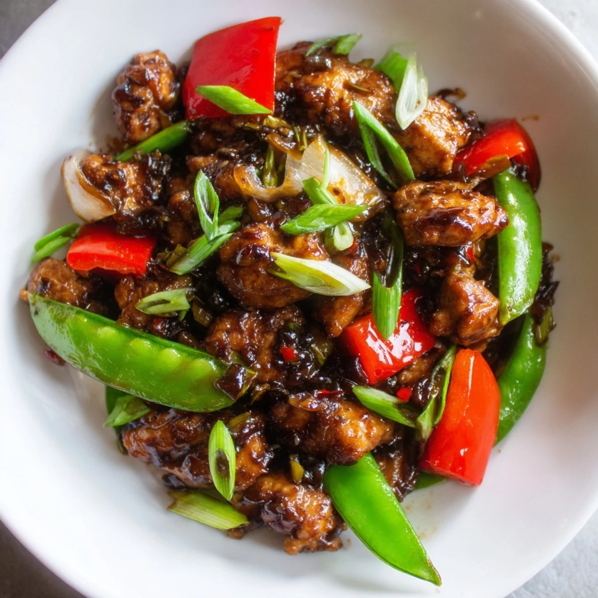 Tender Stir Fried Chinese Garlic Chicken tossed with crisp bell peppers and snow peas