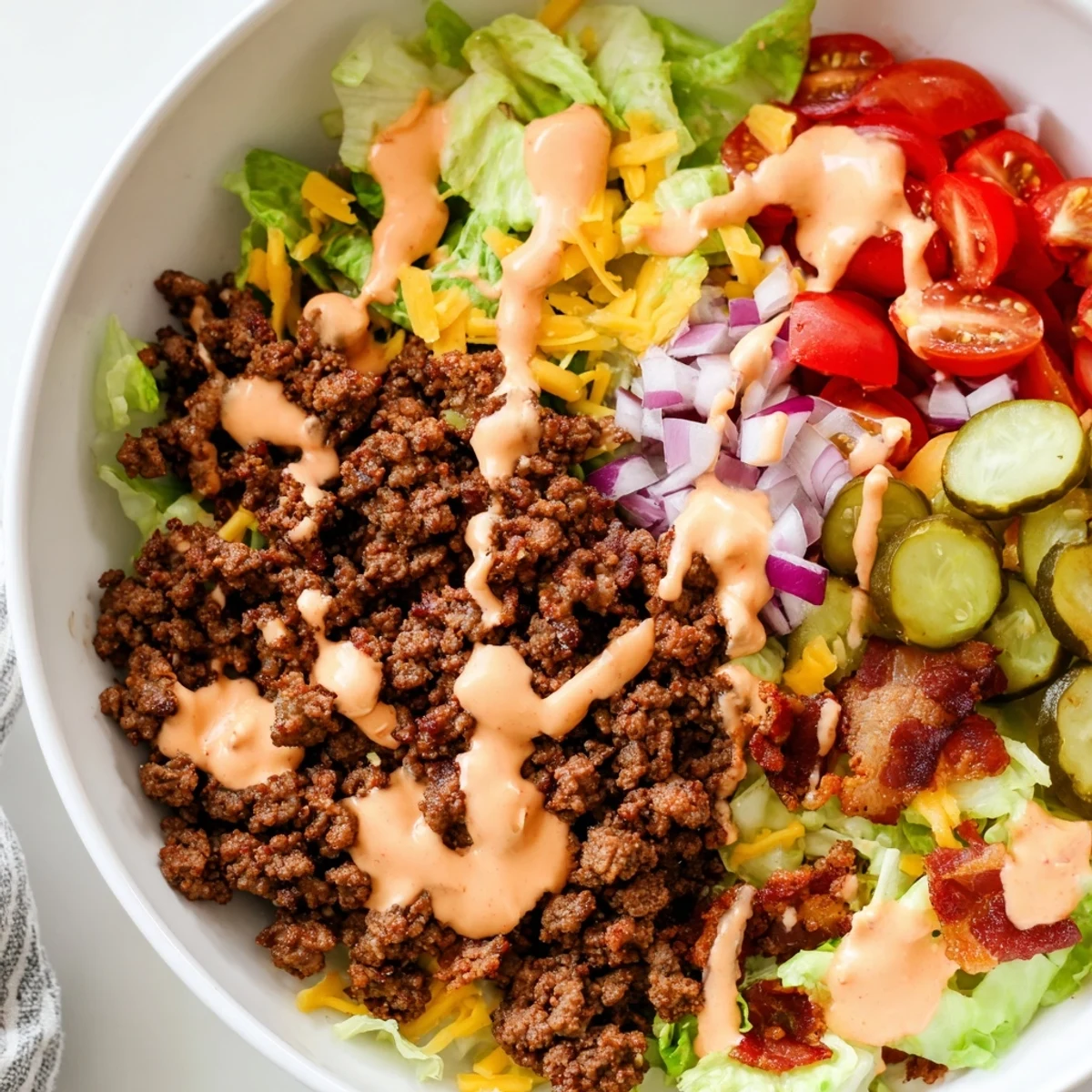 Savory Burger Bowls drizzled with special sauce, garnished with bacon and fresh tomatoes