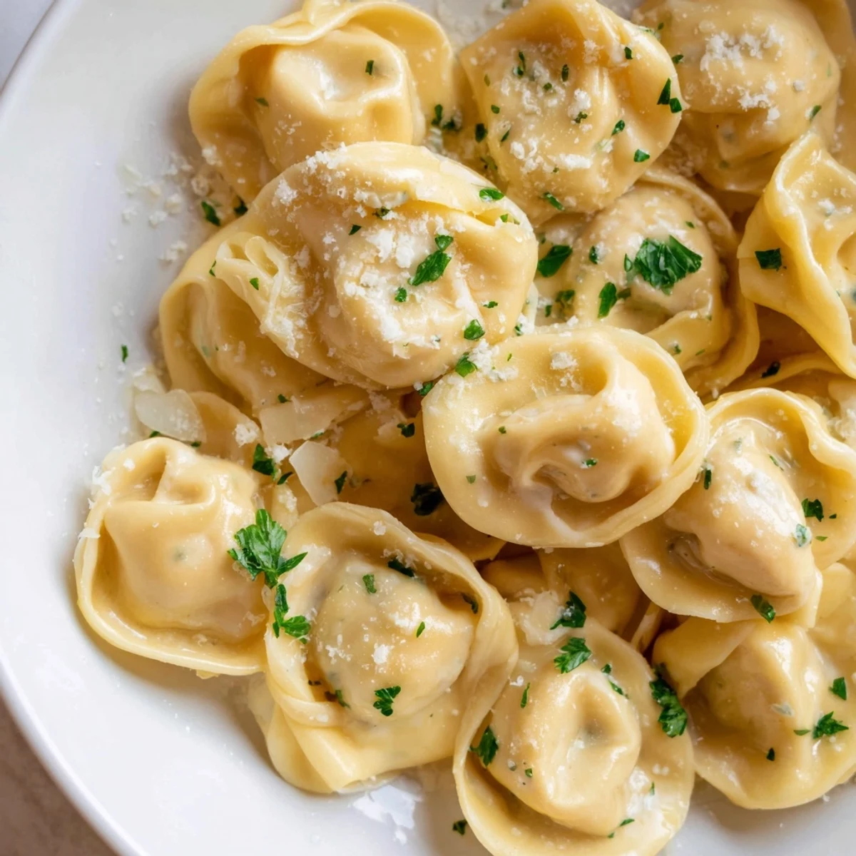 Golden chicken tortellini draped in silky Parmesan cream sauce on a white plate