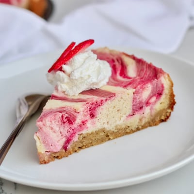Tangy rhubarb ribbons marble through this silky keto cheesecake on a golden plate